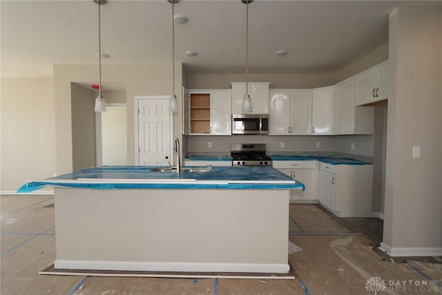 kitchen with white cabinets, pendant lighting, appliances with stainless steel finishes, a center island with sink, and a sink