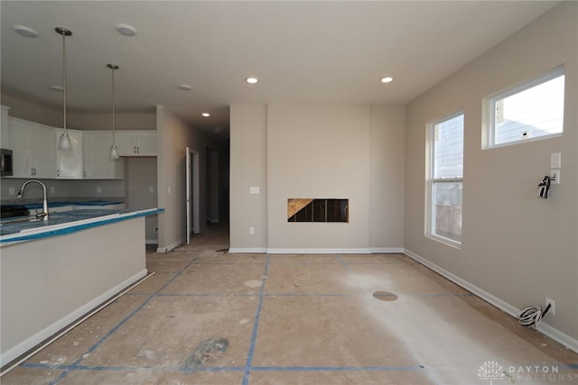 kitchen featuring a fireplace, baseboards, white cabinetry, and decorative light fixtures