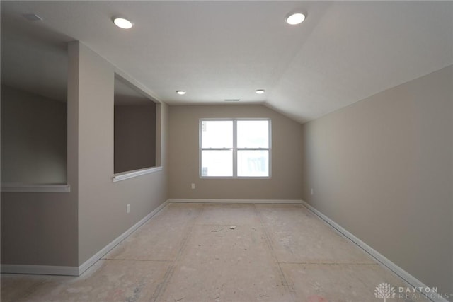 empty room featuring lofted ceiling and baseboards