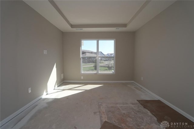 spare room featuring baseboards and a tray ceiling