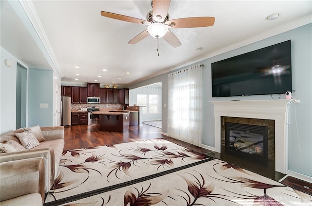 living room featuring ceiling fan, ornamental molding, a fireplace, and dark wood-type flooring