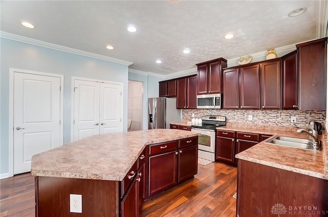 kitchen featuring sink, appliances with stainless steel finishes, dark hardwood / wood-style floors, a center island, and crown molding