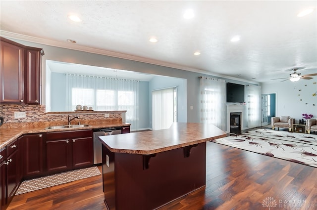 kitchen featuring dishwasher, a breakfast bar area, dark hardwood / wood-style flooring, a center island, and ceiling fan