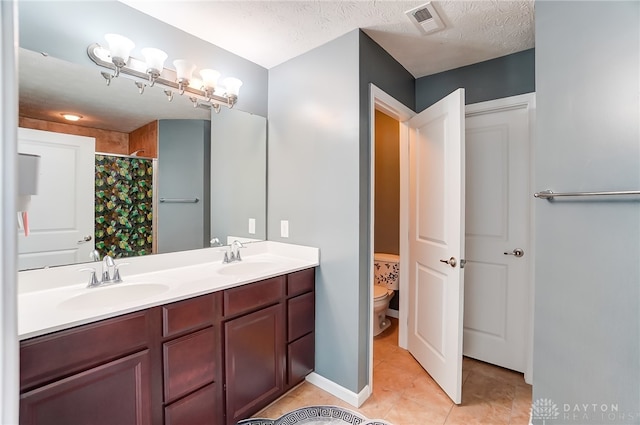 bathroom with tile patterned floors, a textured ceiling, vanity, and toilet