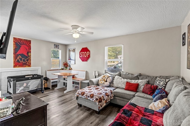 living room with a textured ceiling, hardwood / wood-style floors, and ceiling fan