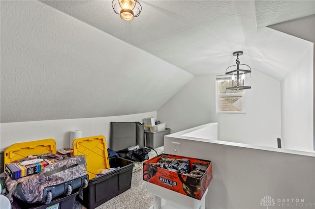 rec room with carpet floors, a textured ceiling, lofted ceiling, and a notable chandelier