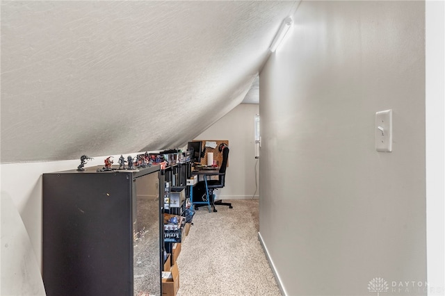 carpeted home office featuring lofted ceiling and a textured ceiling