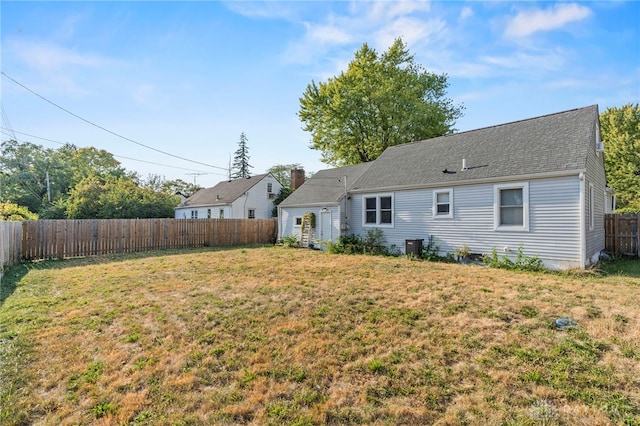 back of house with central air condition unit and a yard