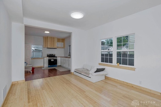 unfurnished living room with sink and light wood-type flooring