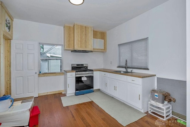 kitchen with sink, light hardwood / wood-style flooring, stainless steel range with gas stovetop, ventilation hood, and white cabinets