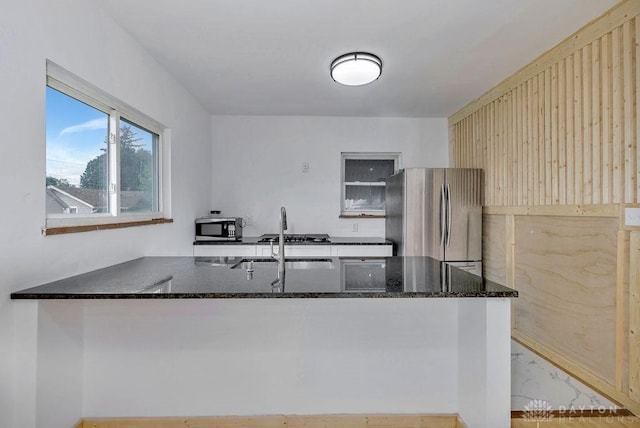 kitchen featuring dark stone countertops, sink, stainless steel appliances, and kitchen peninsula