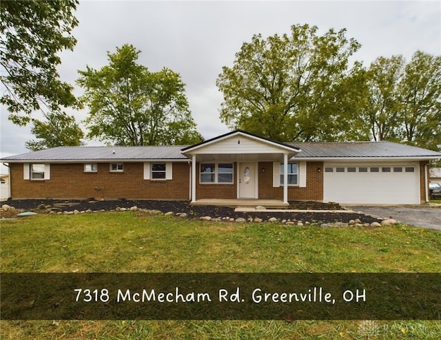 single story home featuring a front lawn, covered porch, and a garage