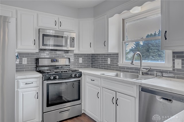 kitchen with stainless steel appliances, sink, decorative backsplash, and white cabinetry