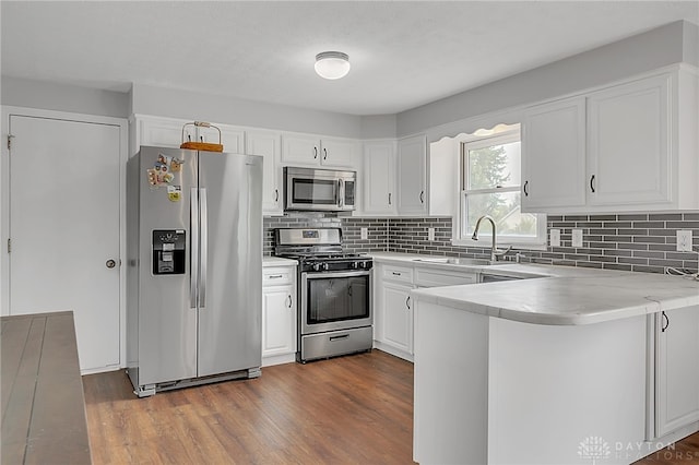 kitchen featuring sink, kitchen peninsula, dark wood-type flooring, white cabinetry, and appliances with stainless steel finishes