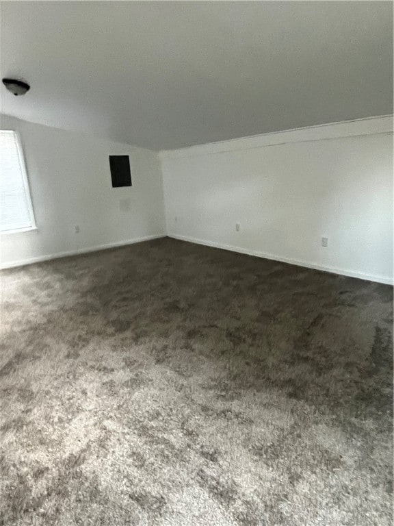 spare room with vaulted ceiling and dark colored carpet