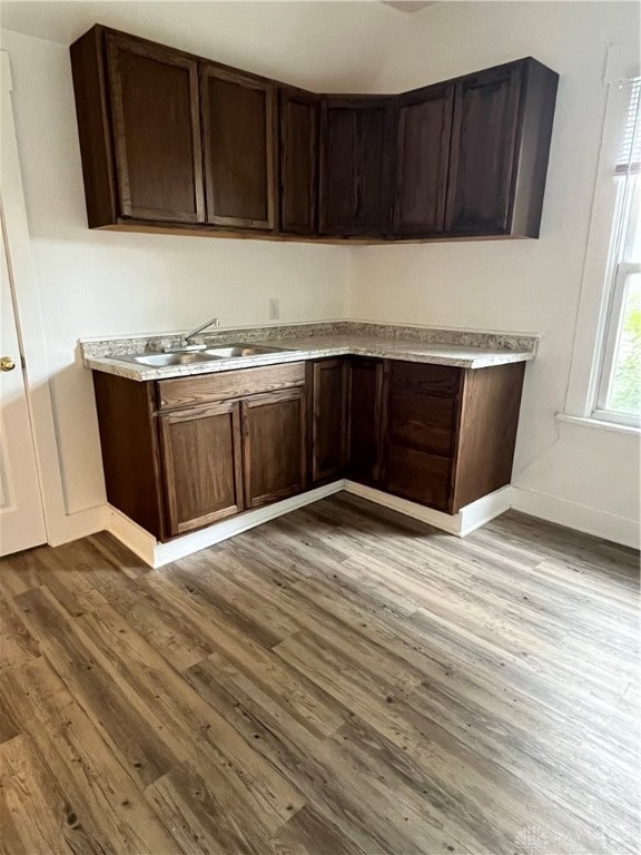 kitchen with sink, dark brown cabinets, and light hardwood / wood-style floors