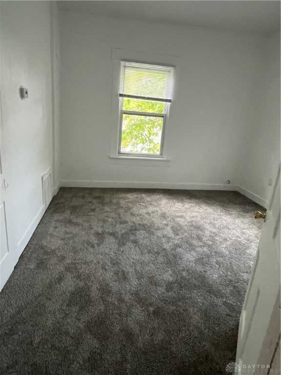 unfurnished room with dark colored carpet