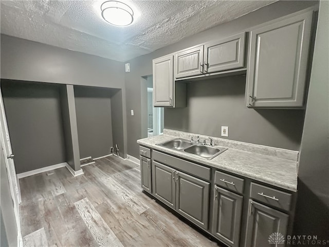 kitchen featuring a textured ceiling, sink, light hardwood / wood-style flooring, and gray cabinets