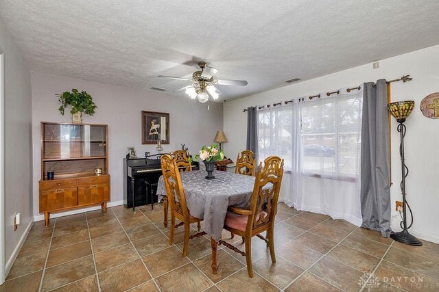 tiled dining room with ceiling fan and a textured ceiling