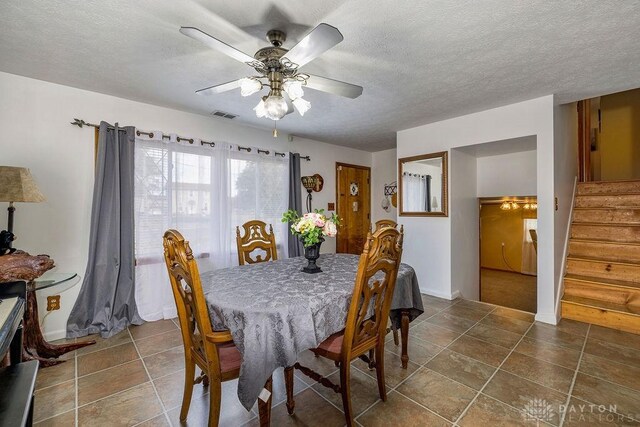 tiled dining room with a textured ceiling and ceiling fan