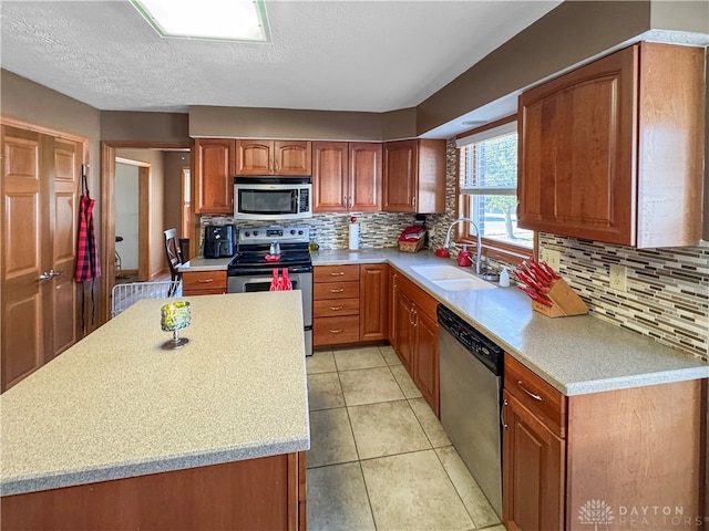 kitchen with light tile patterned floors, sink, a textured ceiling, backsplash, and appliances with stainless steel finishes