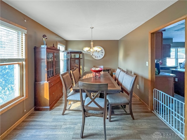 dining space with hardwood / wood-style floors and a notable chandelier