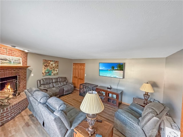 living room featuring a brick fireplace, a textured ceiling, and light wood-type flooring