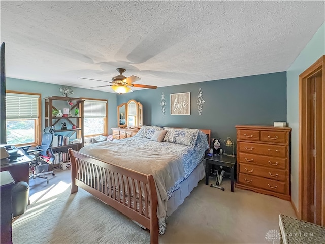 carpeted bedroom featuring ceiling fan and a textured ceiling