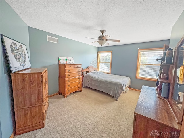 bedroom with ceiling fan, a textured ceiling, and light carpet