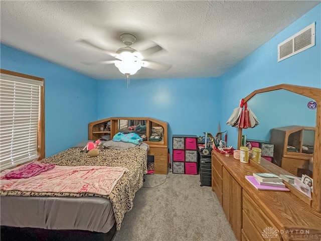 bedroom featuring light carpet, ceiling fan, and a textured ceiling