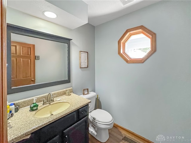 bathroom with hardwood / wood-style floors, vanity, and toilet