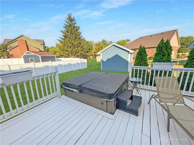 deck featuring a covered hot tub and a yard