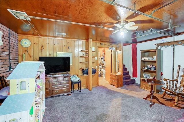 interior space with wood ceiling, brick wall, ceiling fan, dark carpet, and wooden walls