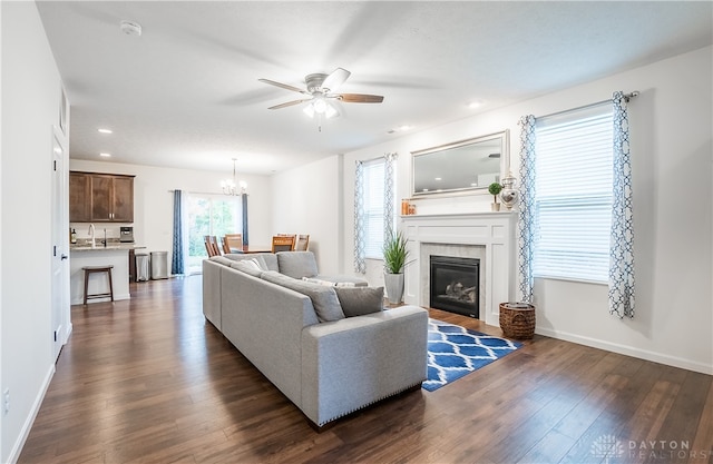 living room featuring ceiling fan with notable chandelier, dark hardwood / wood-style flooring, and a tile fireplace