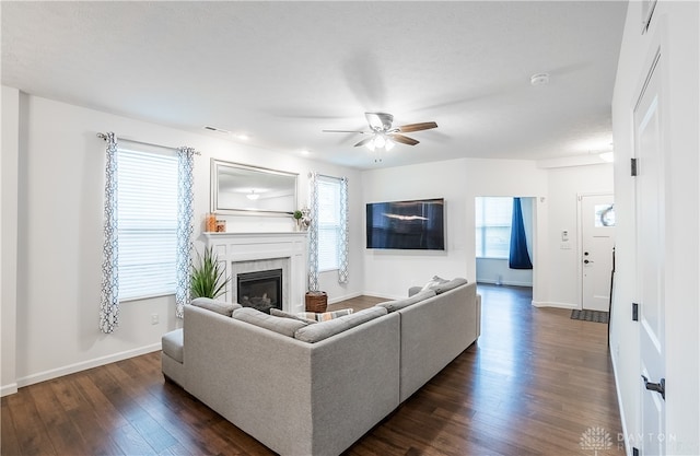 living room with a tile fireplace, dark wood-type flooring, ceiling fan, and plenty of natural light