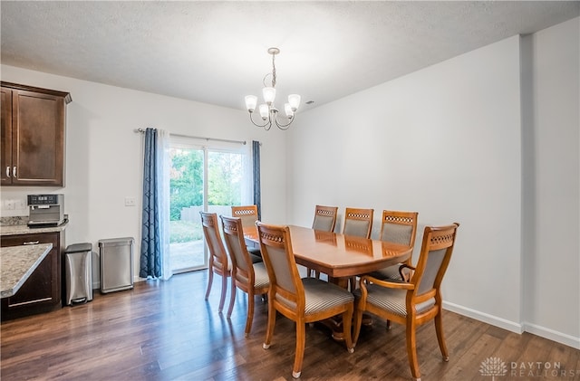 dining area featuring a textured ceiling, dark hardwood / wood-style floors, and a chandelier