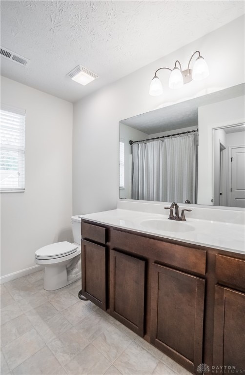 bathroom with a textured ceiling, vanity, and toilet