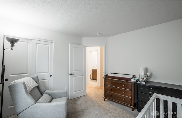 carpeted bedroom with a textured ceiling and a nursery area