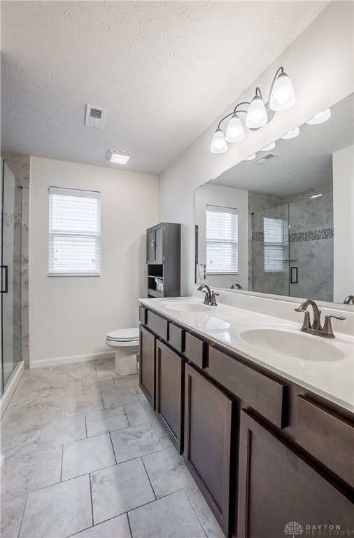 bathroom with toilet, a shower with door, and a healthy amount of sunlight