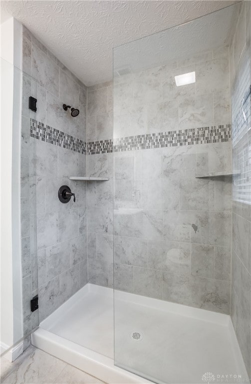 bathroom featuring a textured ceiling and a tile shower