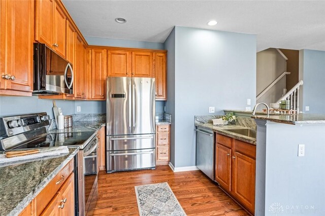 kitchen with sink, stainless steel appliances, stone counters, and dark wood-type flooring