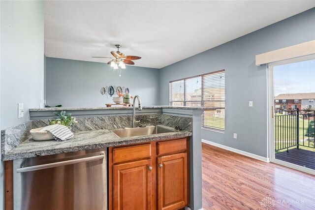 kitchen featuring ceiling fan, sink, stainless steel dishwasher, light hardwood / wood-style floors, and stone countertops