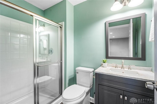 bathroom featuring vanity, a shower with shower door, and toilet