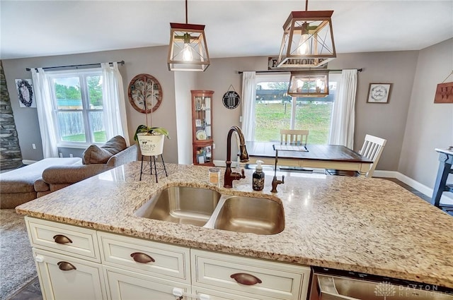 kitchen featuring dishwasher, light stone counters, sink, and decorative light fixtures