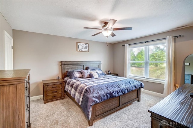 bedroom with ceiling fan, light carpet, and a textured ceiling