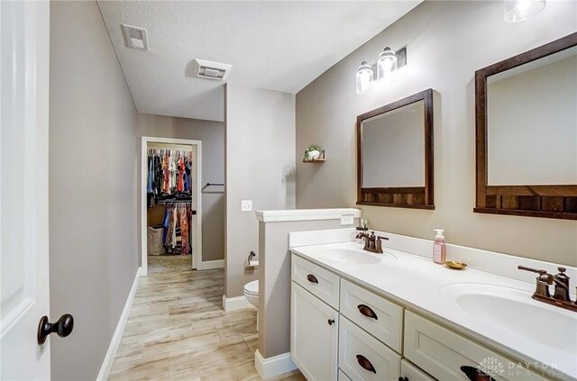 bathroom featuring vanity, a textured ceiling, and toilet