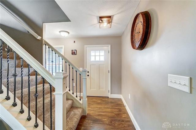 entryway with dark wood-type flooring and a textured ceiling