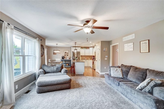 living room with ceiling fan, a textured ceiling, and a wealth of natural light