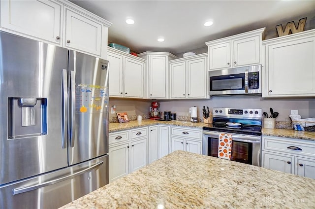 kitchen featuring light stone counters, white cabinets, and stainless steel appliances