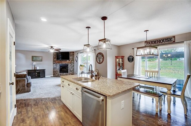 kitchen with stainless steel dishwasher, a kitchen island with sink, sink, and hanging light fixtures